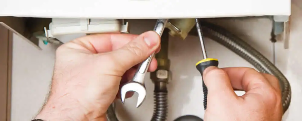Boiler repair technician tightening pipe fittings and connections in Wilmington, NC
