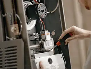 Furnace repair technician inspecting internal components and wiring in Wilmington, NC