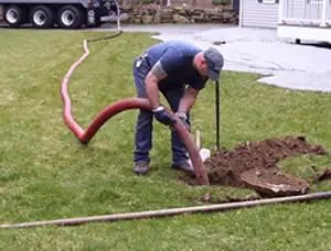 Septic pumping technician servicing a residential septic tank with a vacuum hose in Wilmington, NC