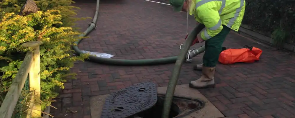 Septic tank cleaning technician servicing a septic tank with a vacuum hose in Wilmington, NC