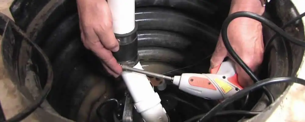 Sump pump installation technician connecting PVC discharge piping in Wilmington, NC