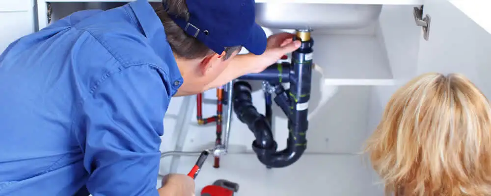 Plumber repairing under-sink drain pipes and fittings in Wilmington, NC